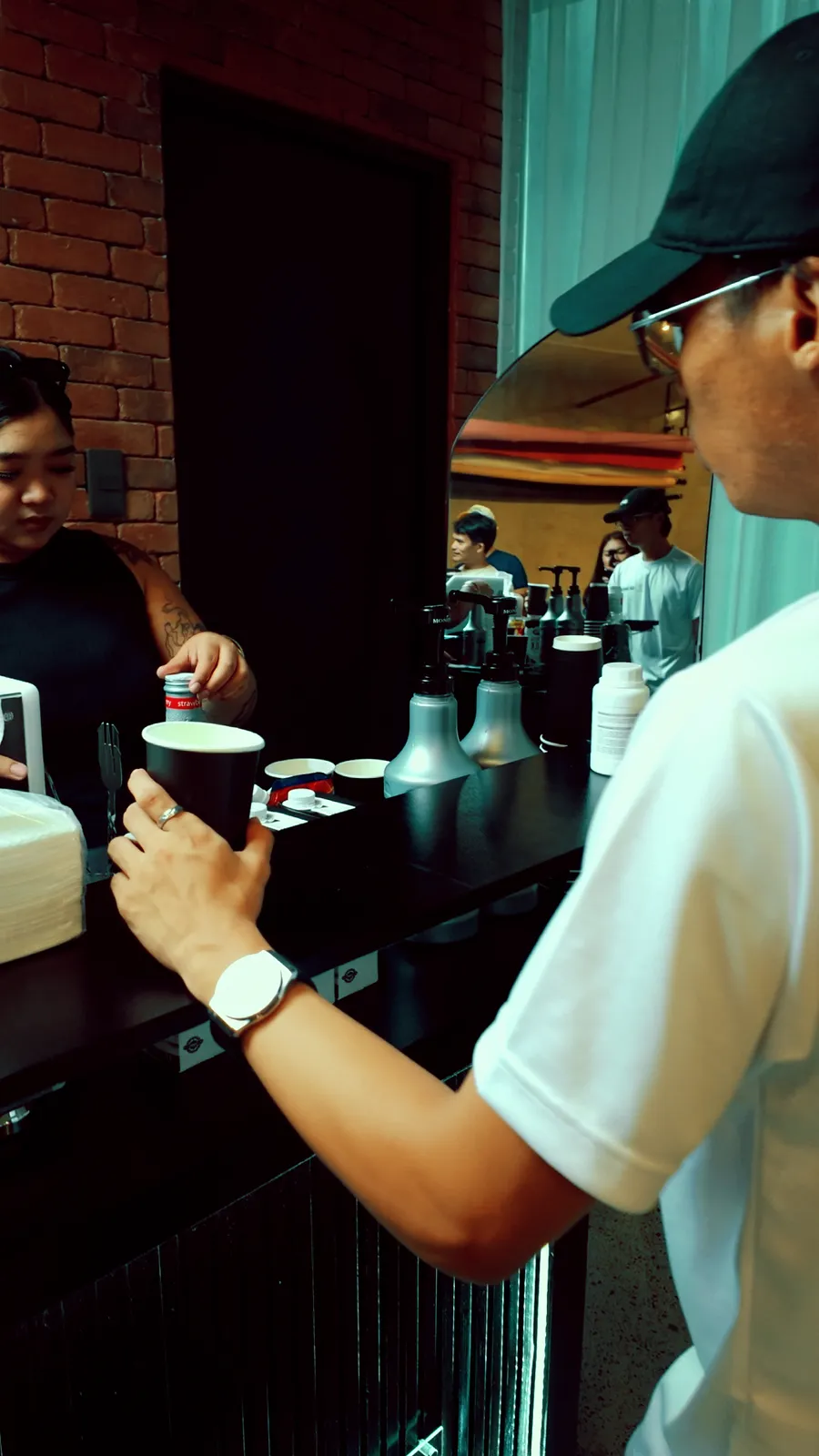 A guest taking a black paper cup from a barista across the cart counter.