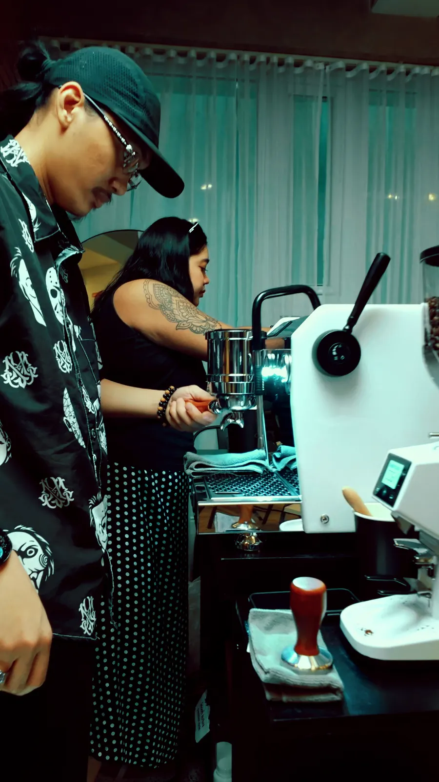 Two baristas working side by side at the cart's espresso machine and grinder.
